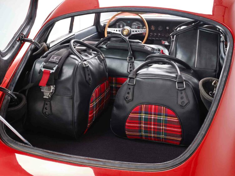 Set de bagages Coventry en cuir pleine fleur et drap de laine tartan, assortis à l’habitacle. La sangle rappelle le harnais de compétition.